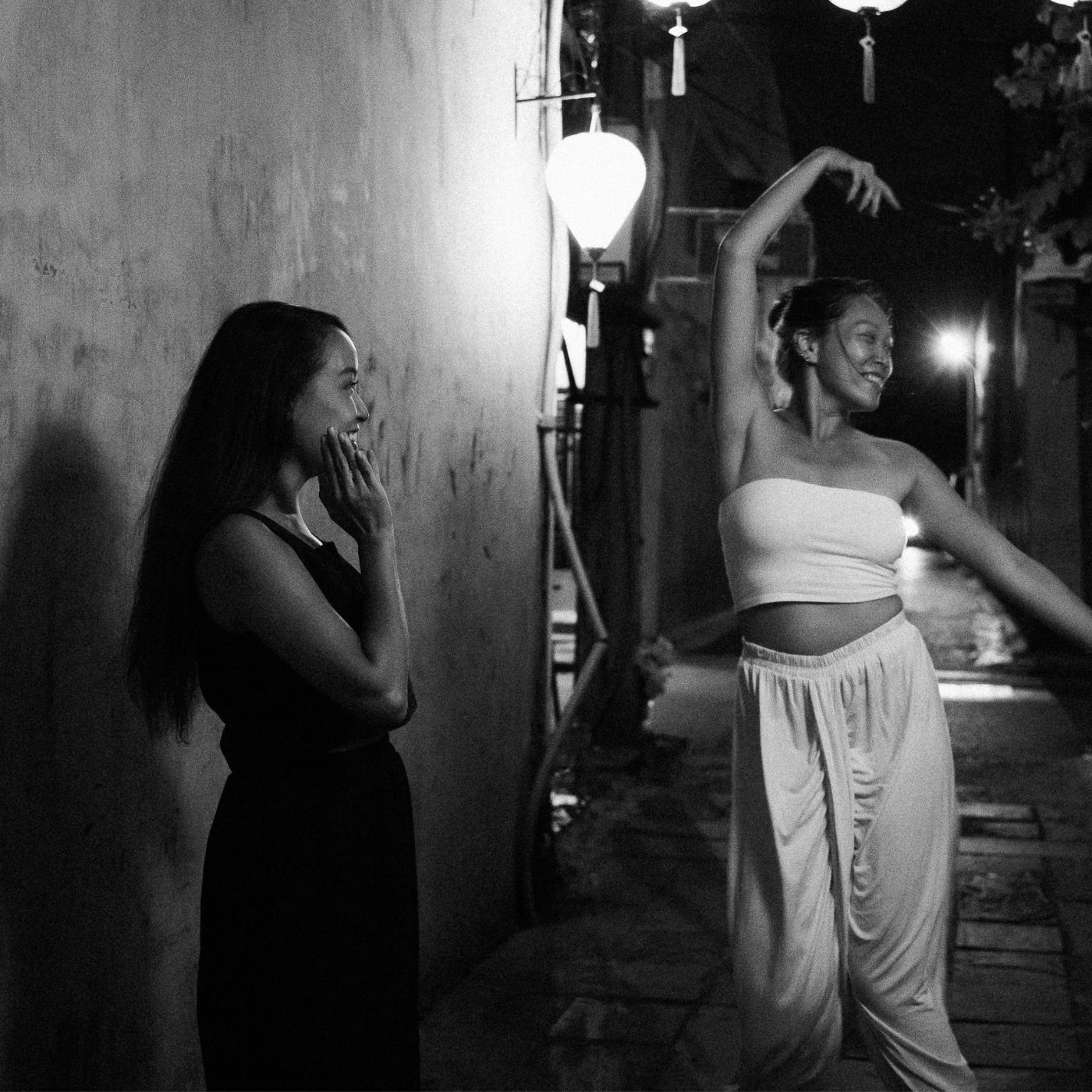 Two women enjoying a playful night conversation under street lights in Preston
