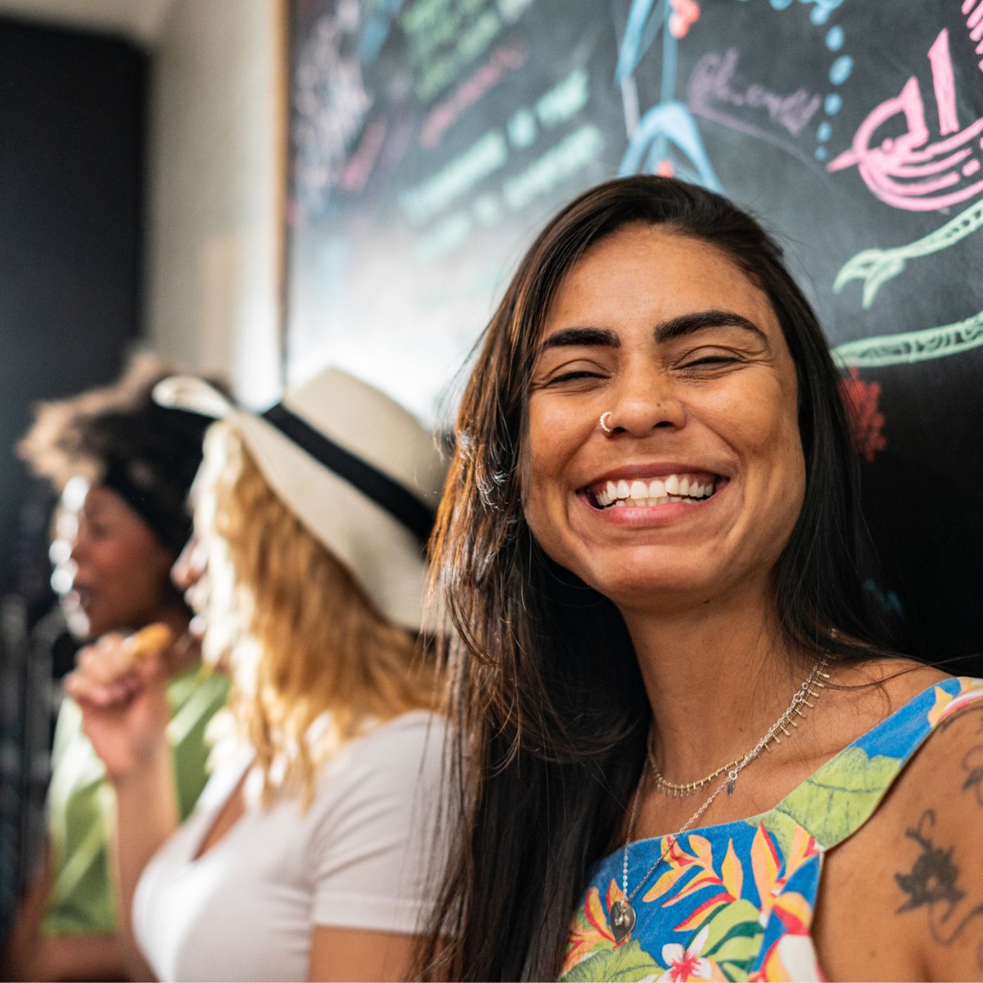 Woman smiling warmly indoors with friends and colorful wall art in Castlewellan