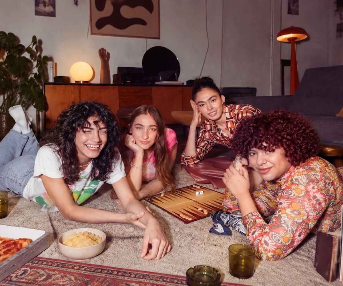Four women on a rug beside a wooden sideboard and lamp, playing backgammon – our Sheffield guide to meeting people