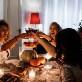 Friendship apps UK: four women raising a toast over a candlelit dinner with new friends