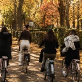 Friendship Month: four women cycling together along a tree-lined path in autumn