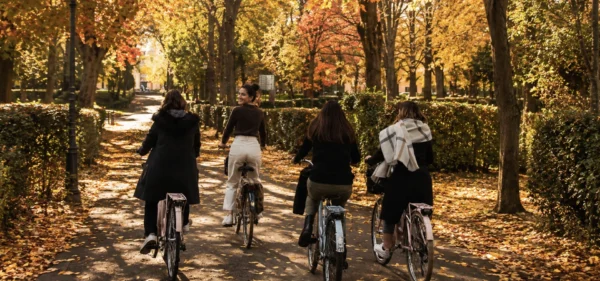 Friendship Month: four women cycling together along a tree-lined path in autumn